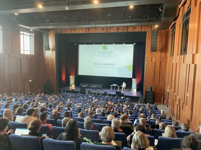 Conférence ANDICAT dans un auditorium, intervenant sur scène face à un large public.