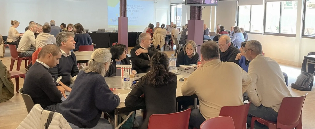 Participants réunis en ateliers de travail autour de tables lors d’une rencontre du réseau.