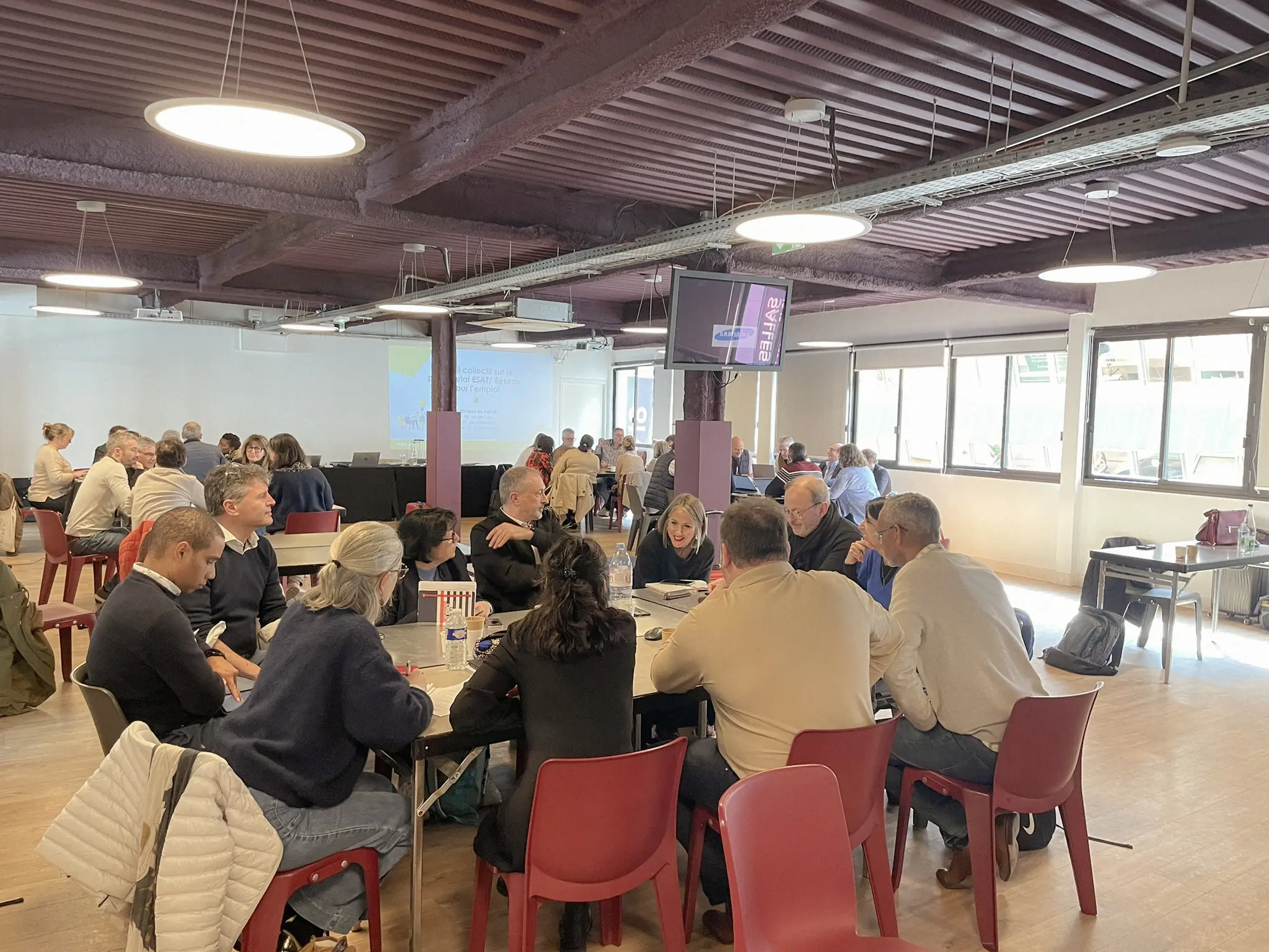 Participants réunis en ateliers de travail autour de tables lors d’une rencontre du réseau.
